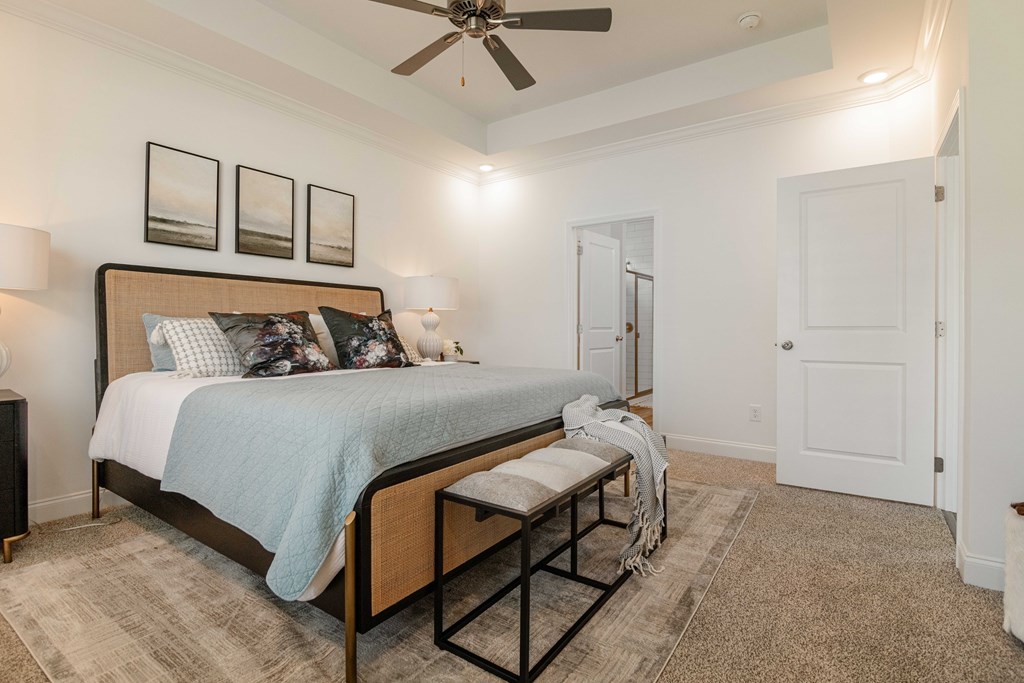 A bedroom with a bed, bench, and pictures on the wall.