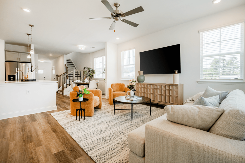 A living room with a white couch, a yellow armchair, and a black television.