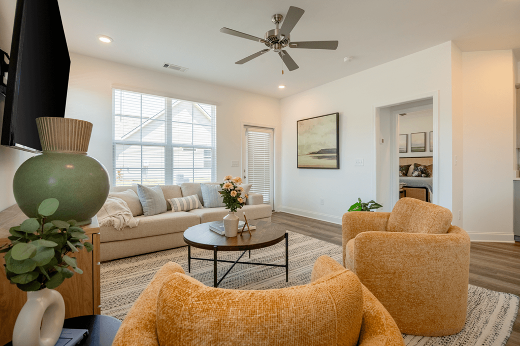 A living room with a sofa, chairs, and a ceiling fan.