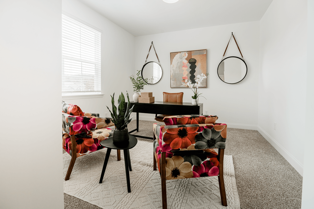 A living room with a floral patterned chair and a small table with a vase on it.