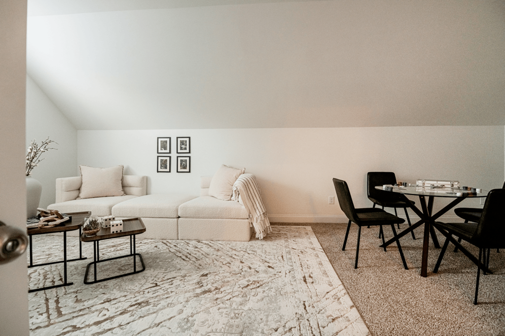 A living room with a white couch, a coffee table, and a dining table with chairs.