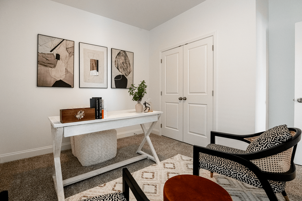 A white table with a plant on it and a chair with a pillow on it.