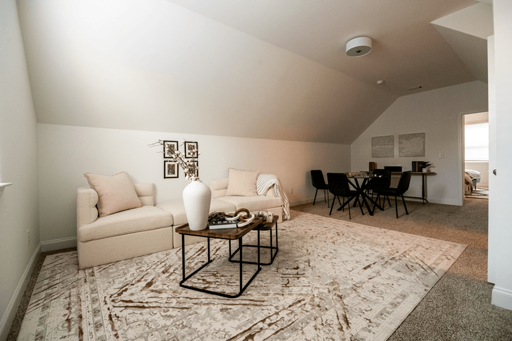 A living room with a beige couch, a white chair, a coffee table, and a rug.