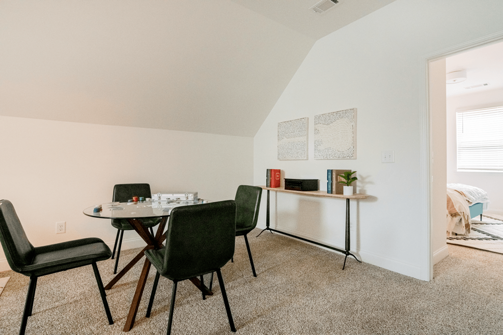 A room with a white wall and a round table with chairs around it.