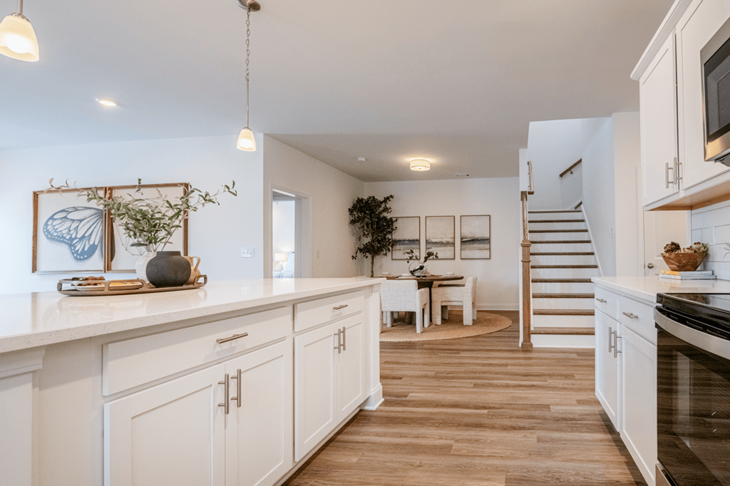 A kitchen with white cabinets and a wooden floor.