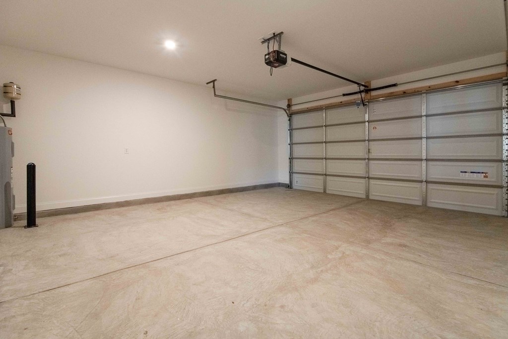 A spacious garage with a white wall and a closed white garage door.
