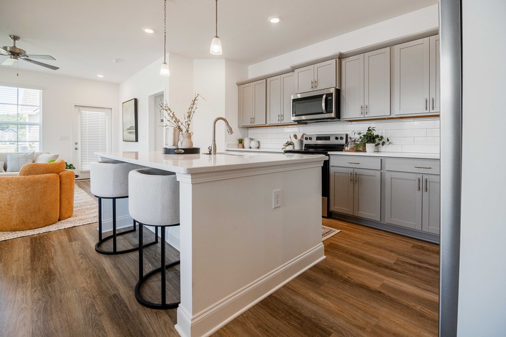A kitchen with a white counter and bar stools.