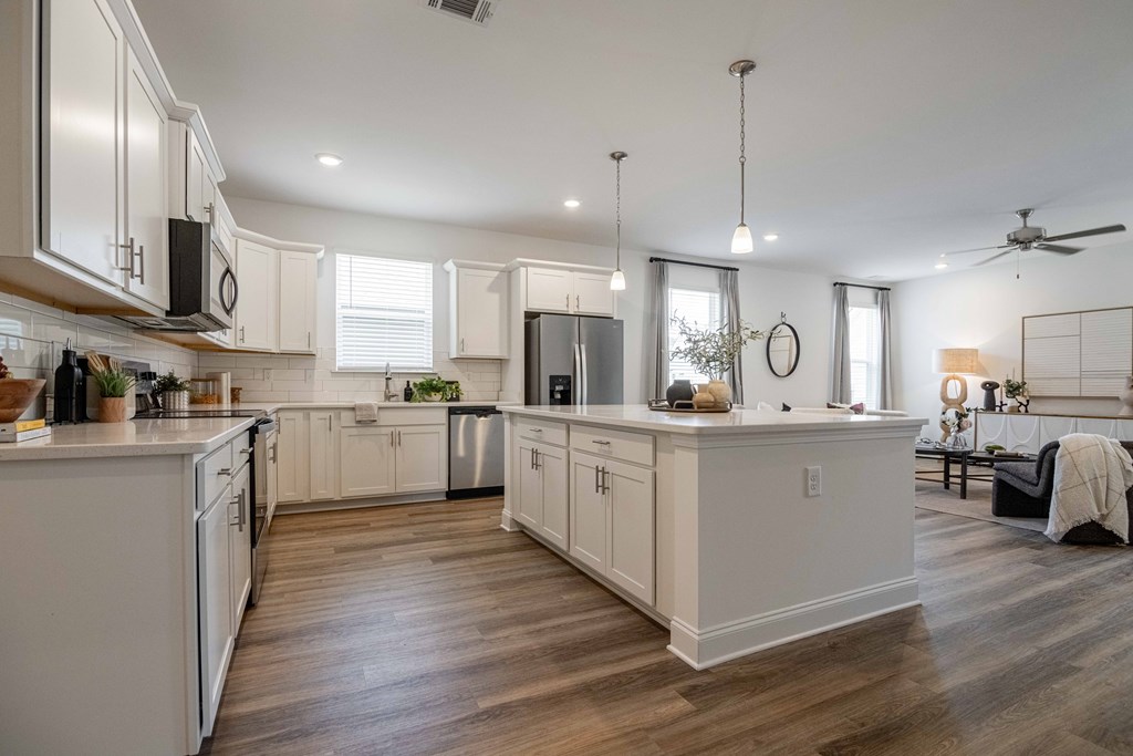 A modern kitchen with white cabinets and a wooden floor.