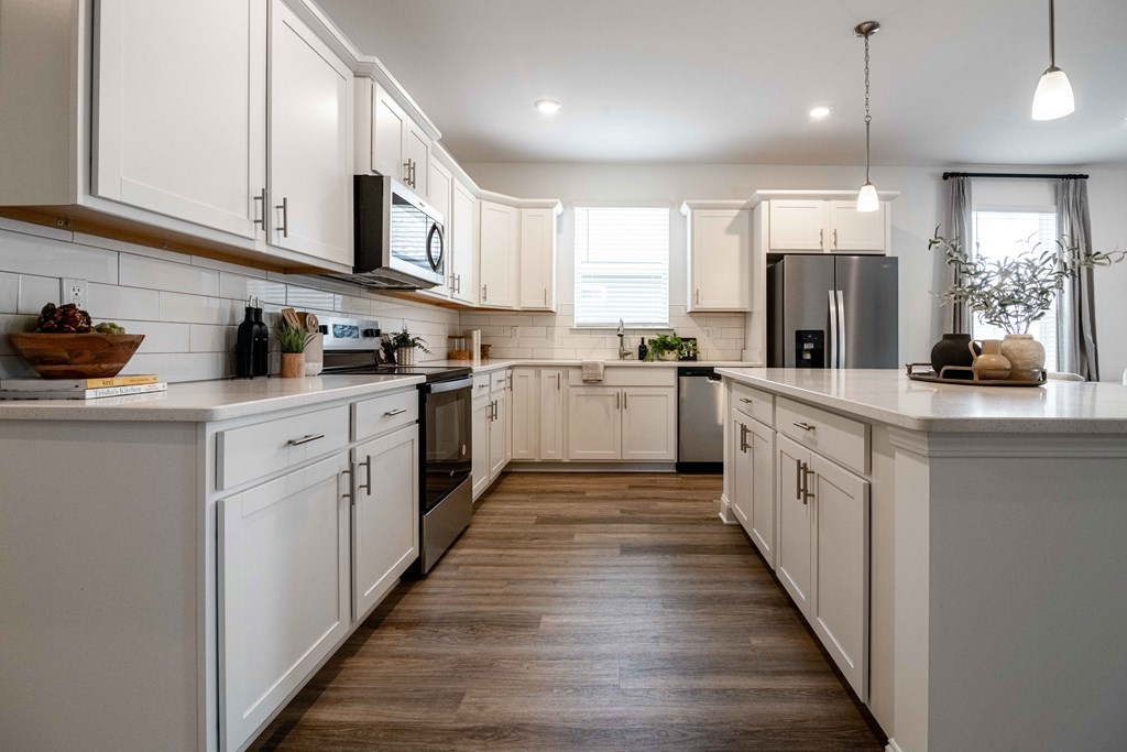 A modern kitchen with white cabinets and wooden floors.