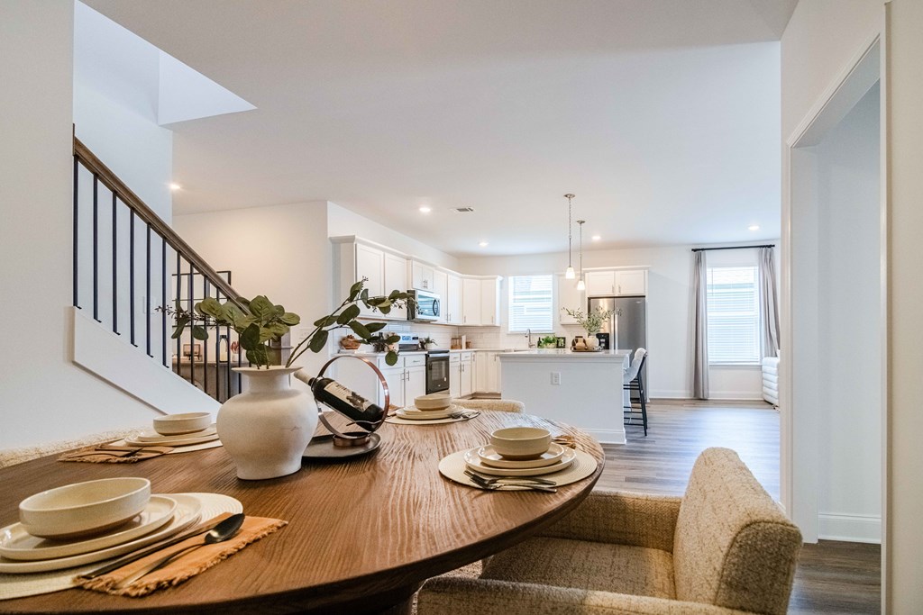 A dining table set with plates and bowls is in the foreground of a bright and modern kitchen.