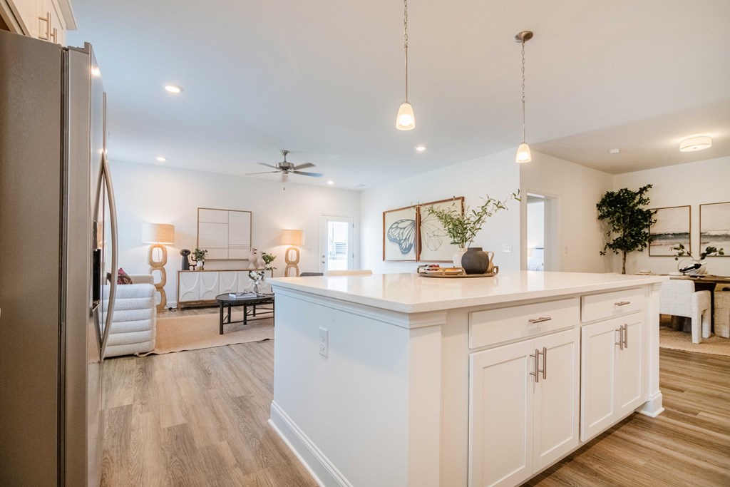 A kitchen with white cabinets and a wooden floor.
