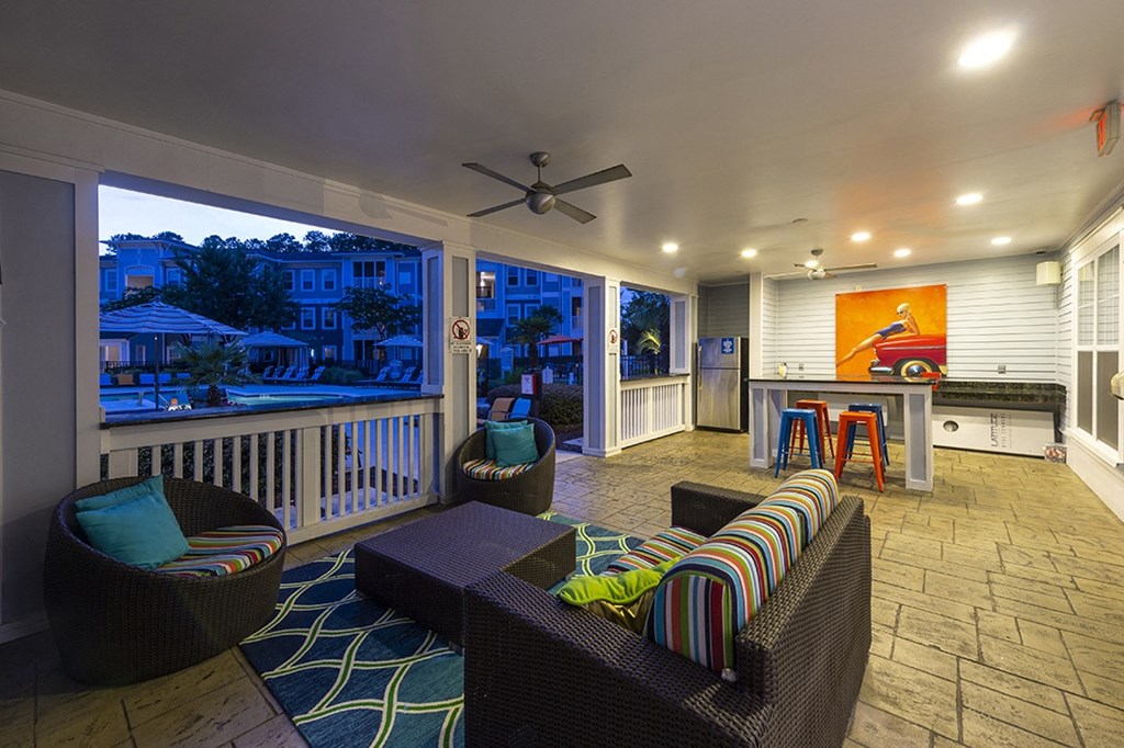 a large covered porch with furniture and a bar and a kitchen