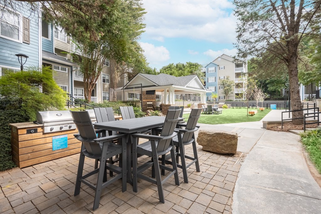 an outdoor patio with a table and chairs and a grill
