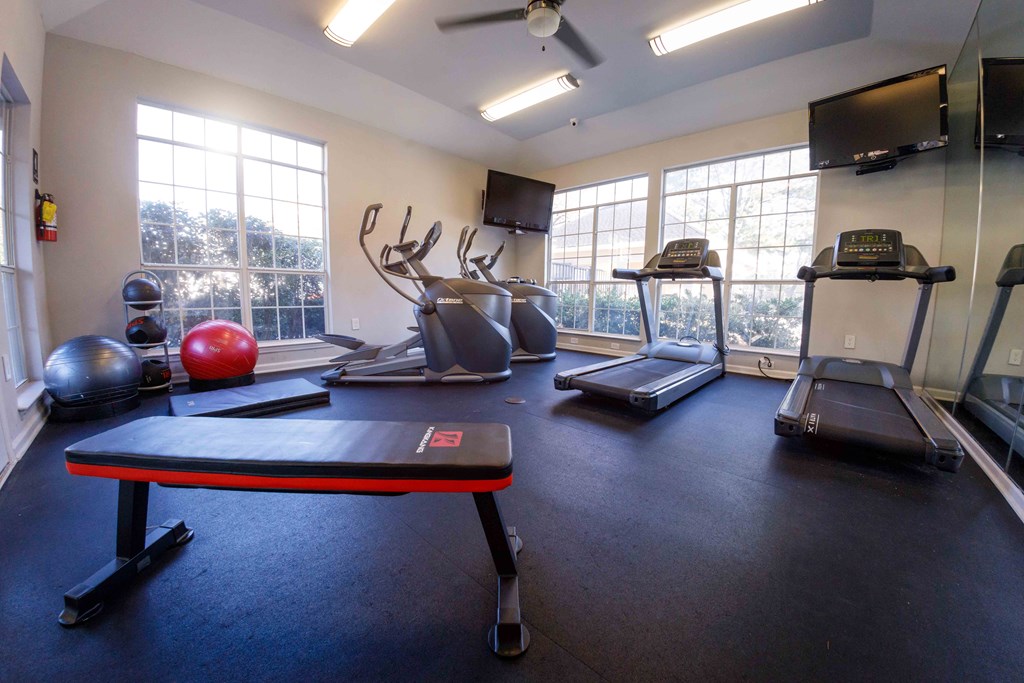 a gym with a row of exercise equipment and windows