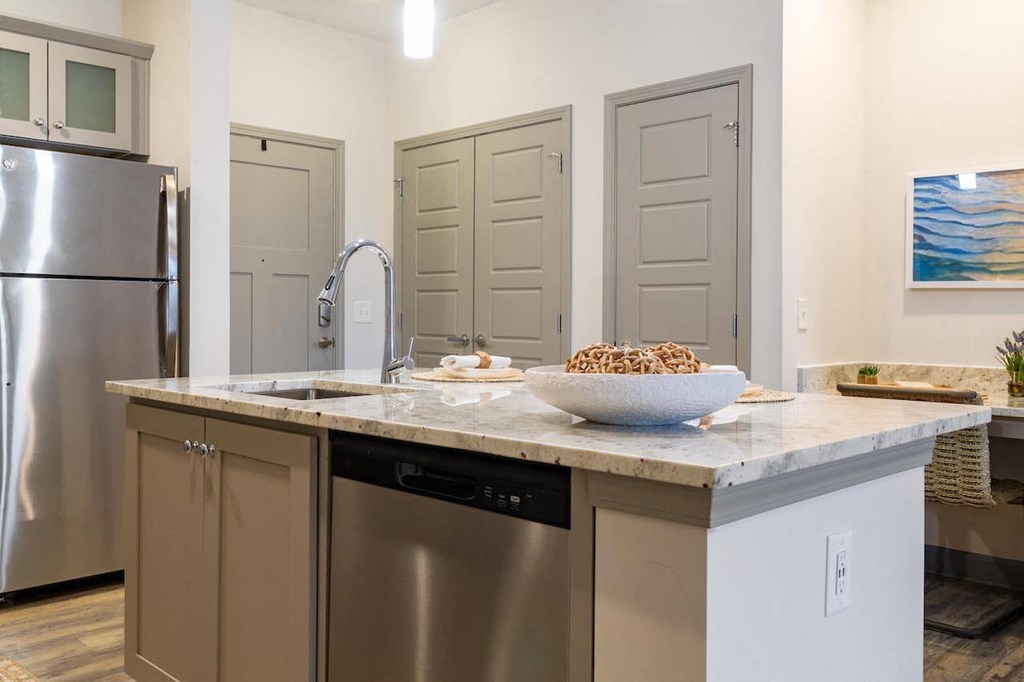 A kitchen with a stainless steel refrigerator, a sink, and a bowl of cereal on the counter.