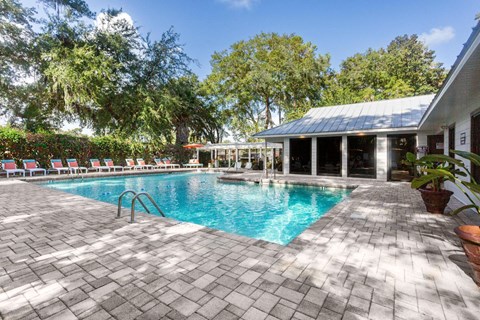 A pool surrounded by trees and a building.