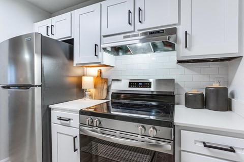 a white kitchen with stainless steel appliances and white cabinets