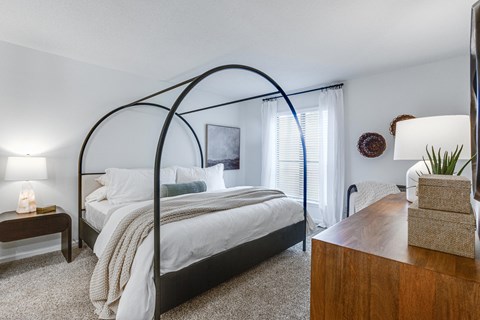 A bedroom with a canopy bed and a wooden dresser.