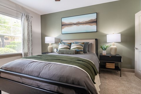 A bedroom with a large bed and a painting on the wall.