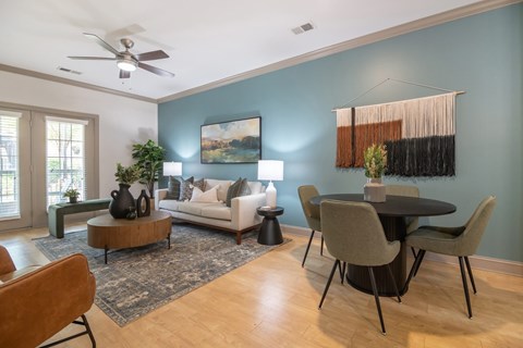 A living room with a white couch, a coffee table, and a dining table with chairs.