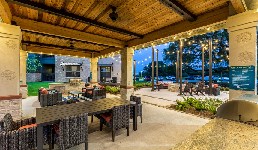 a covered patio with tables and chairs and a grill