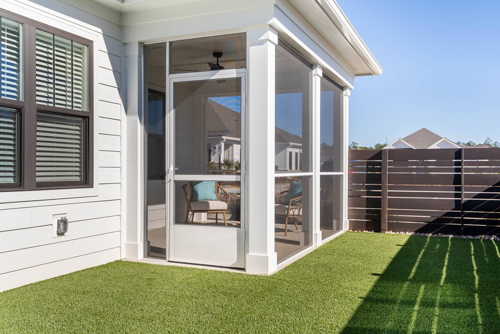 A white apartment home with a glass door and a green lawn in front.