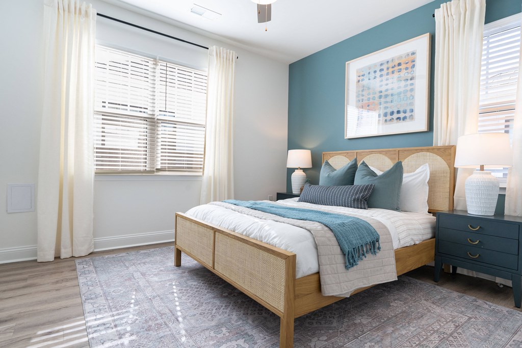 A bedroom with a bed, nightstand, and window with curtains.