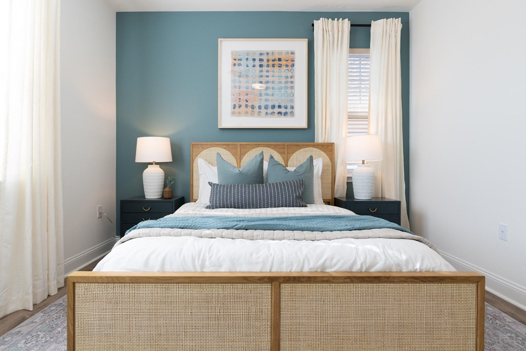 A bedroom with a bed, two lamps, and a painting on the wall.