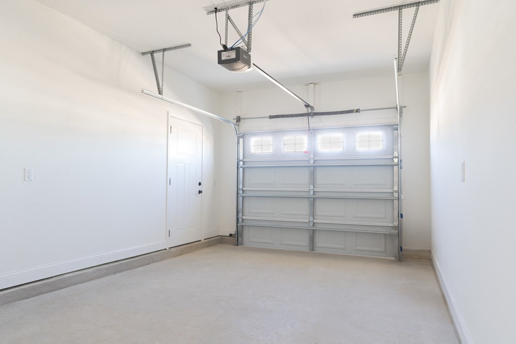 A garage with a white door and a grey garage door opener.