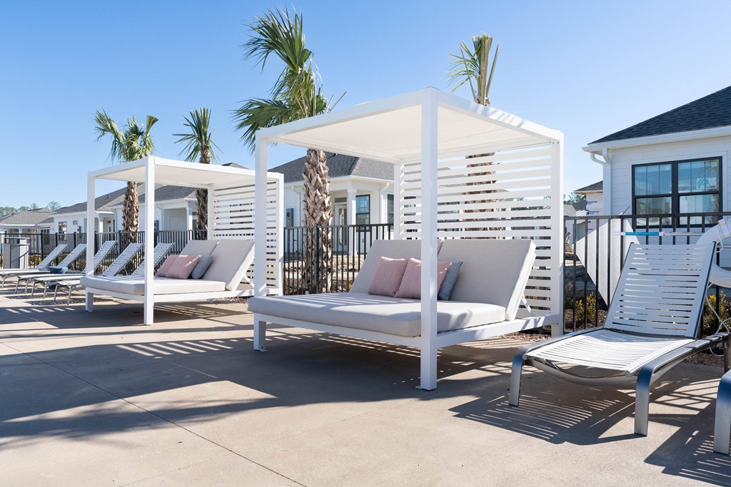 a patio with white lounge chairs and a white canopy