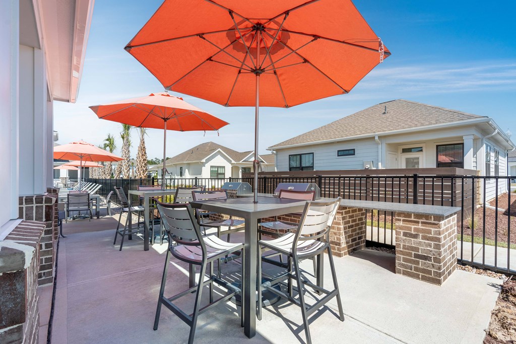A patio with a table and chairs under an orange umbrella.