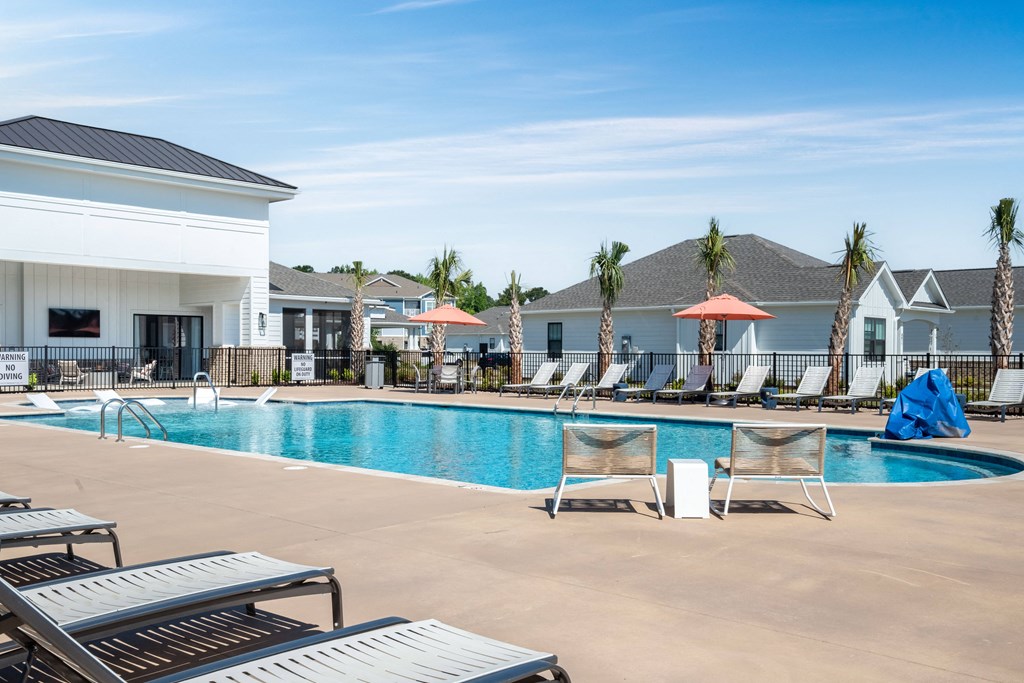 a swimming pool with chairs and umbrellas at the resort on a sunny day
