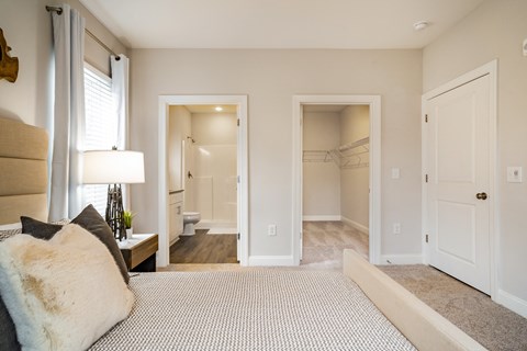 a bedroom with a large bed and a bathroom with a walk in closet