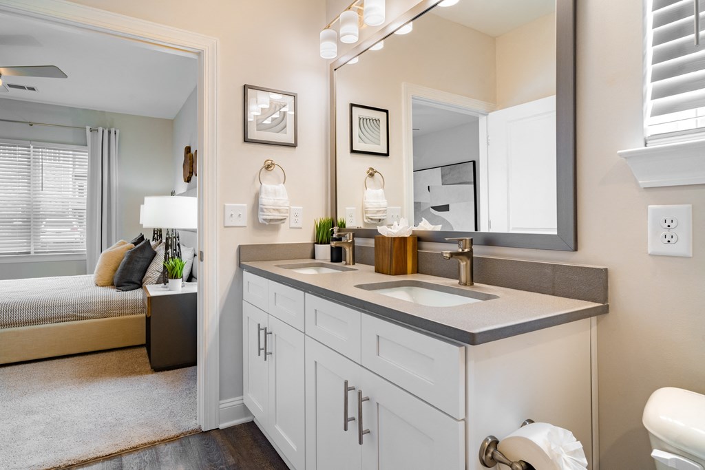 a bathroom with a sink and a mirror and a door to a bedroom
