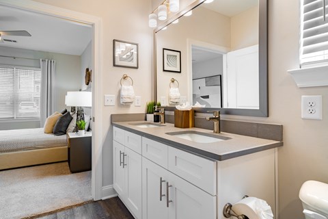 a bathroom with a sink and a mirror and a door to a bedroom