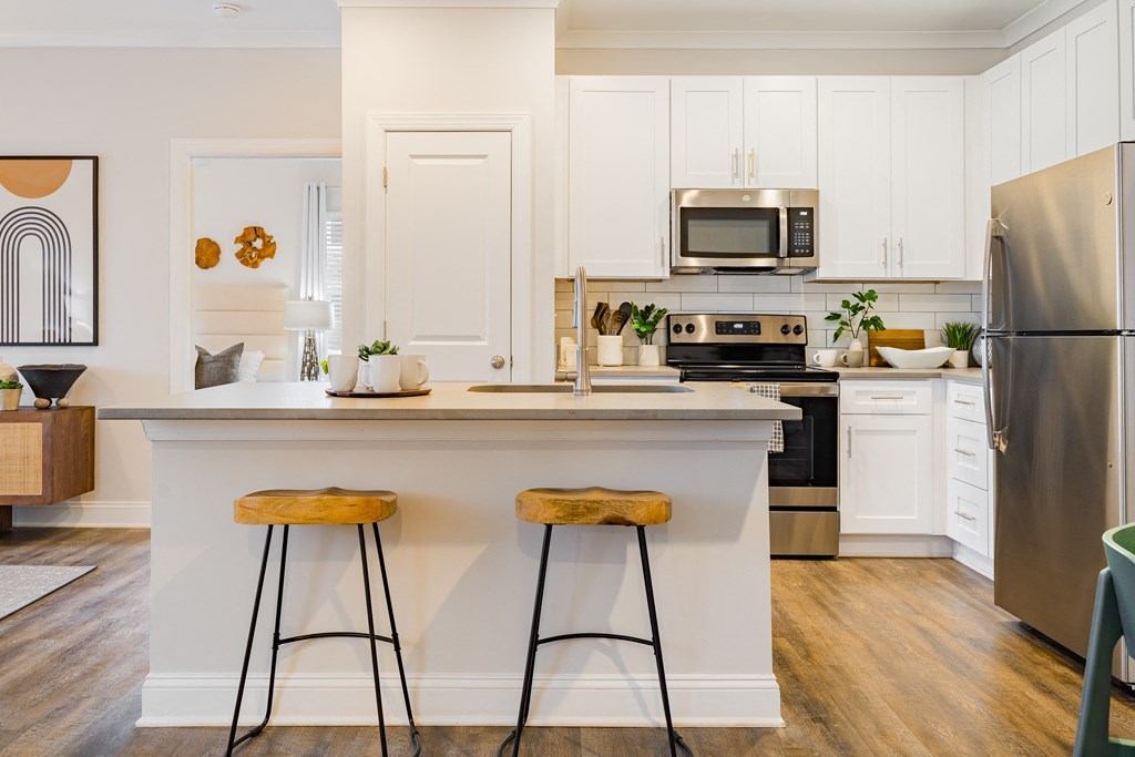a kitchen with white cabinets and a counter top with two stools