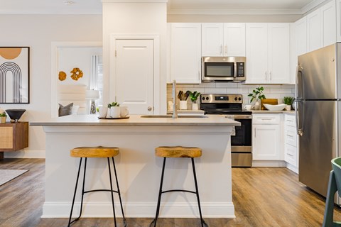 a kitchen with white cabinets and a counter top with two stools