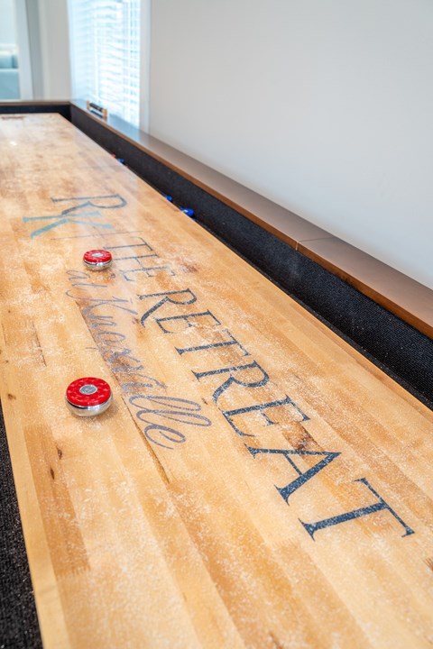a shuffleboard table in a room with the name of the company on it