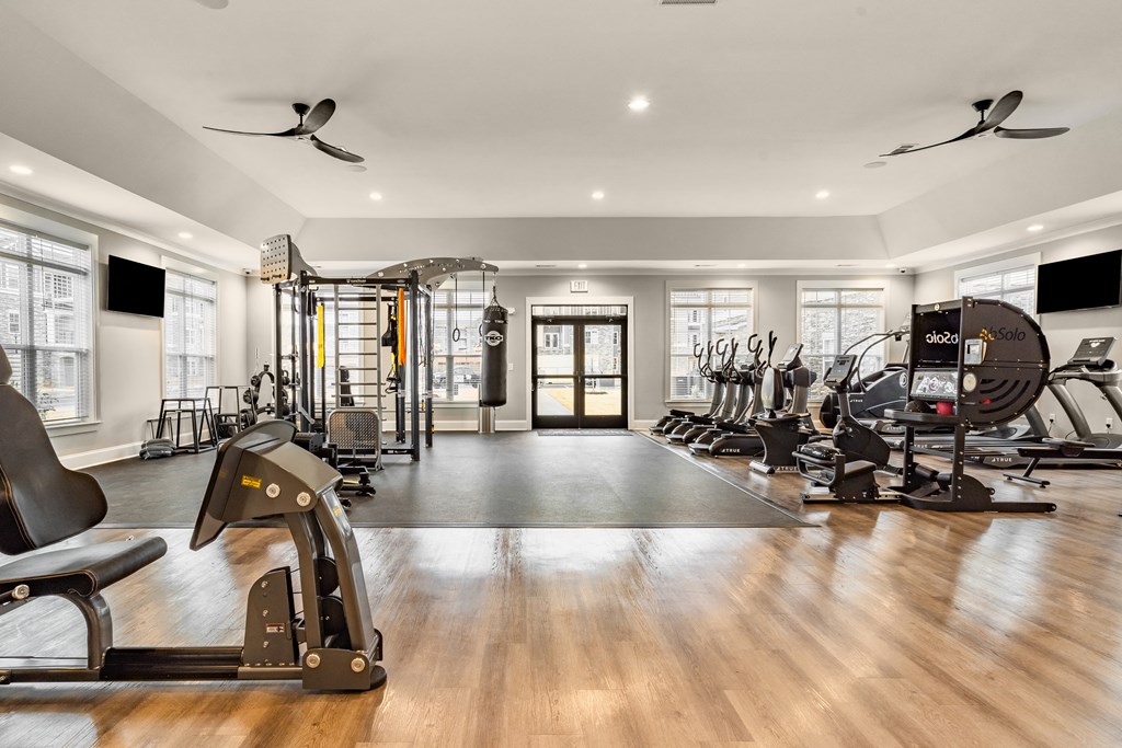 a gym with cardio machines and weights on a hard wood floor