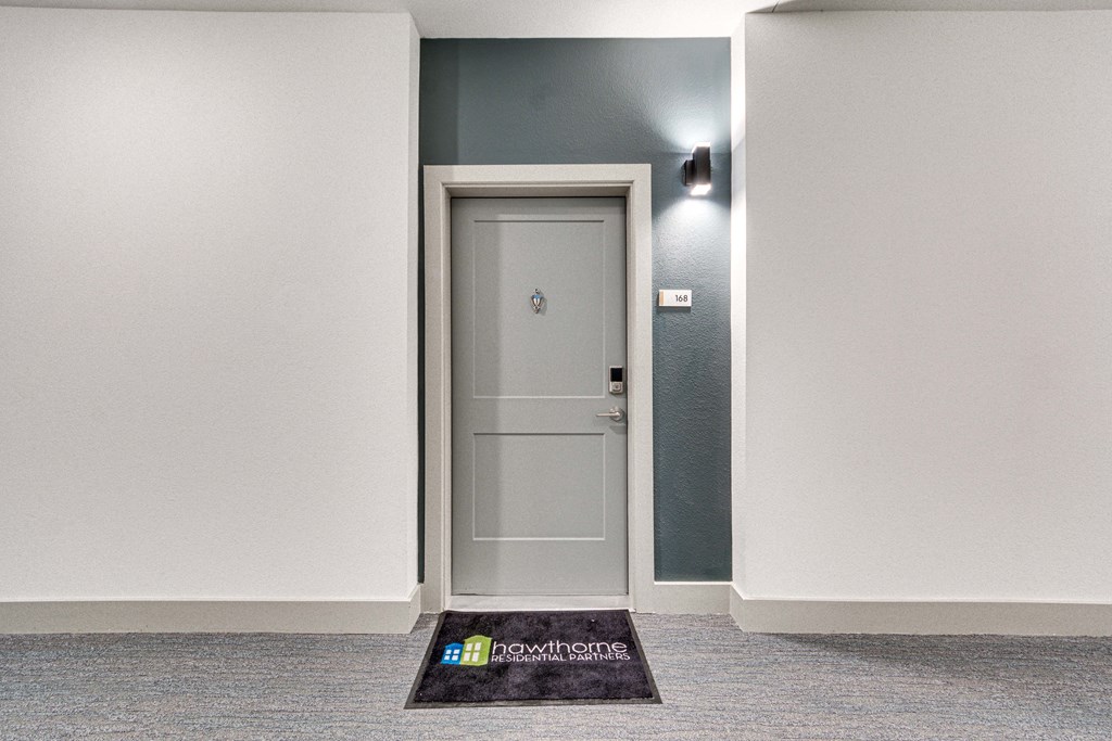 a white door in a room with a door rug and a light on the wall