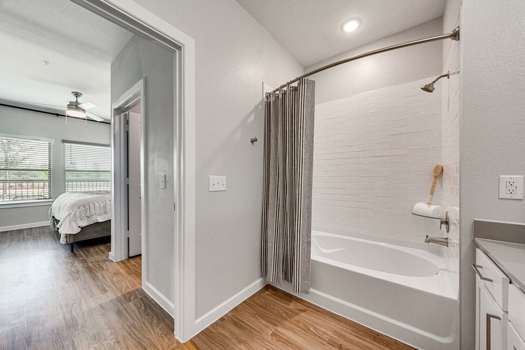 a bathroom with a tub and a shower and a bedroom