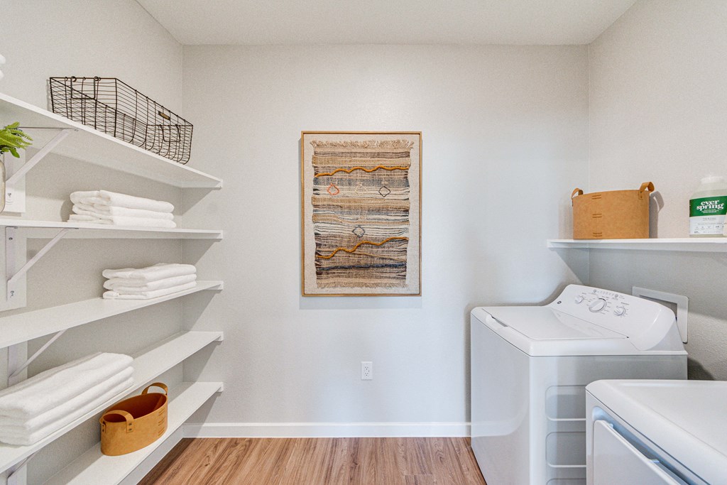 a laundry room with a washer and dryer and shelves with folded towels and