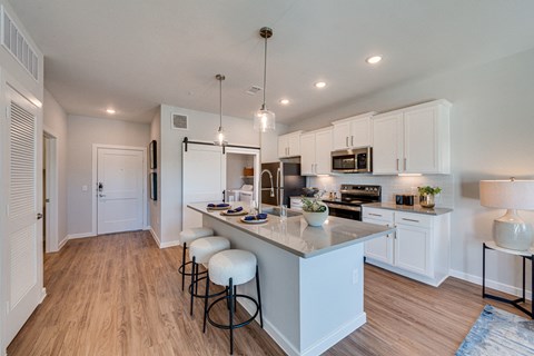 a kitchen with white cabinets and a large island with stools