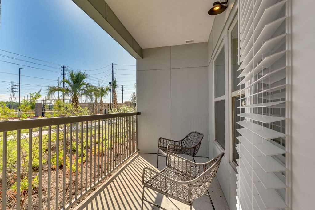 a balcony with two chairs and a view of a palm tree