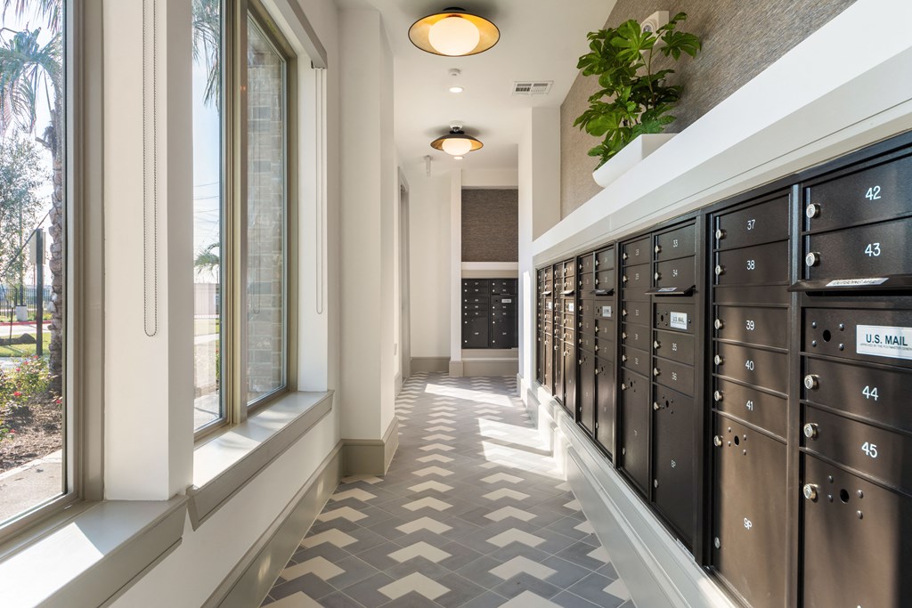 A long hallway with mailboxes on the right and a plant hanging from the ceiling.