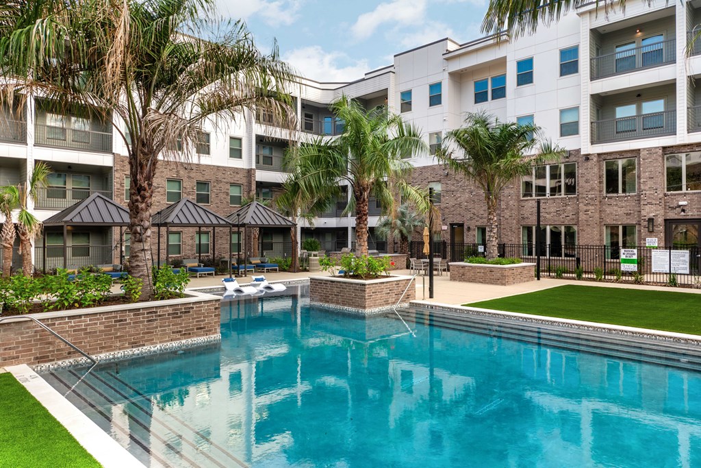 A swimming pool in front of a building with palm trees.