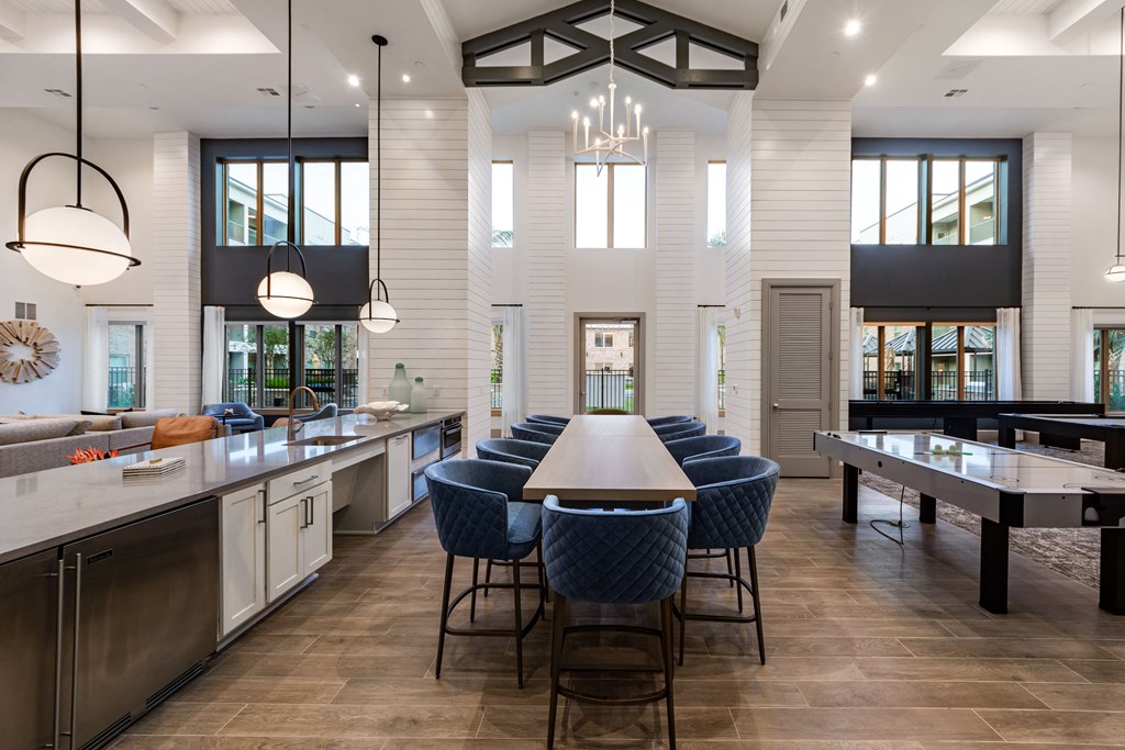 A modern kitchen with a large island and blue chairs.