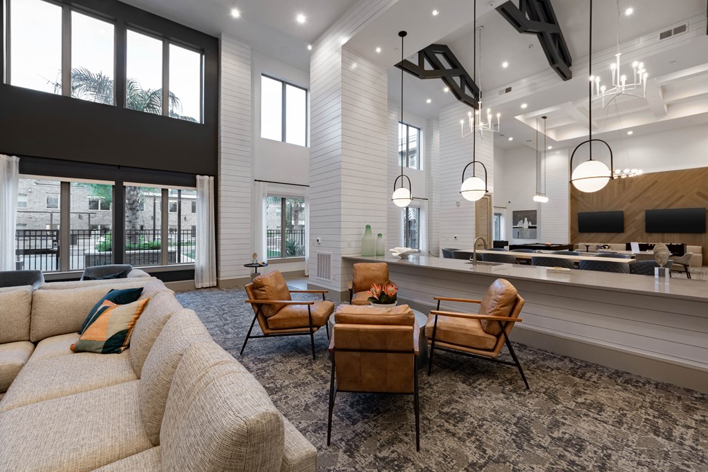 A living room with a couch, chairs, and a kitchen area in the background.