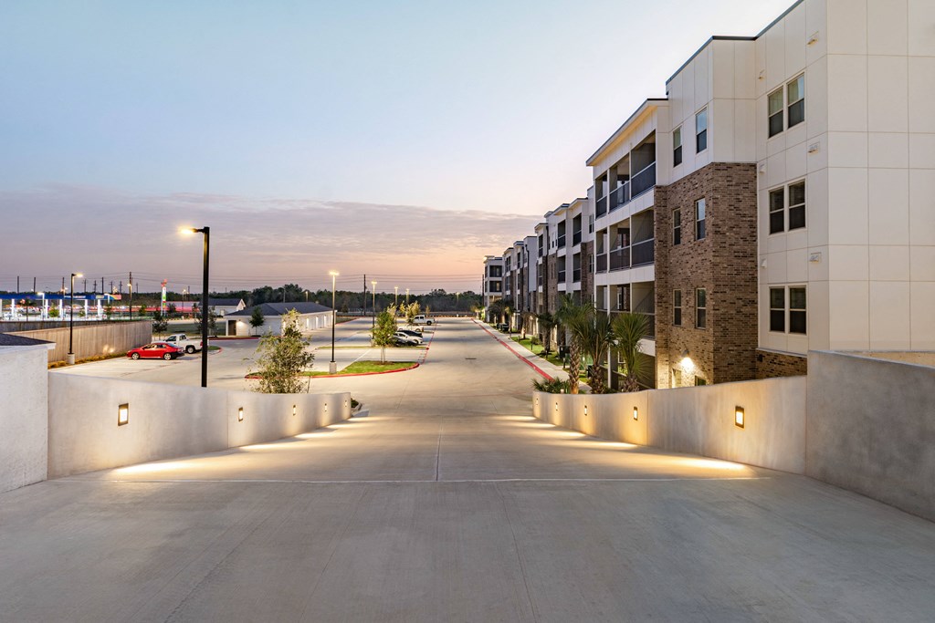A long, empty road with street lights on both sides and apartment buildings on the right.