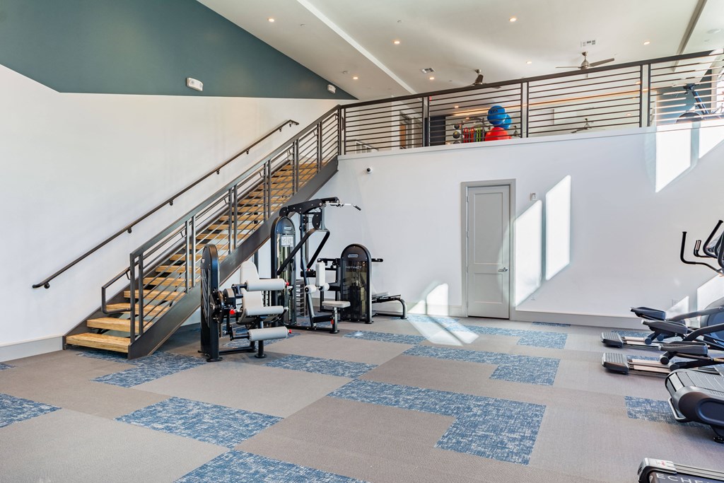 a gym with stairs and exercise equipment and a person on the stairs